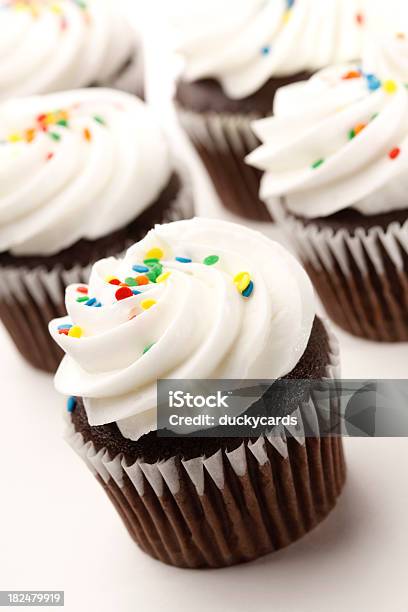 Photo libre de droit de Petits Gâteaux Au Chocolat Avec Glaçage Blanc Colorées Et Confettis En Sucre banque d'images et plus d'images libres de droit de Aliment