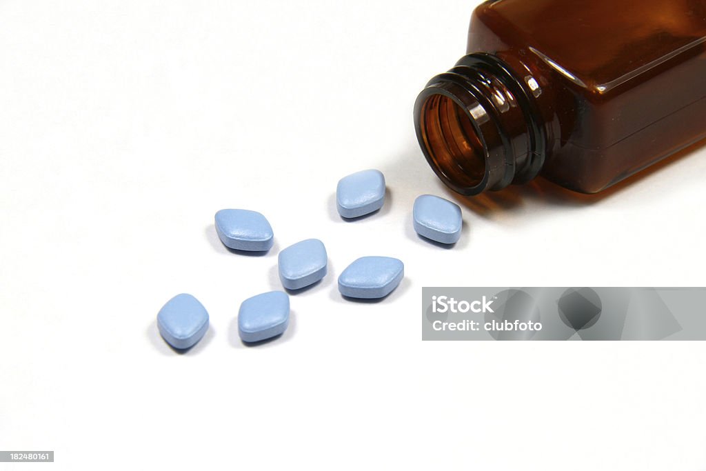 Blue Viagra anti-impotence tablets. Blue Viagra anti-impotence tablets poured out from a bottle onto a white background. Anti-Impotence Tablet Stock Photo