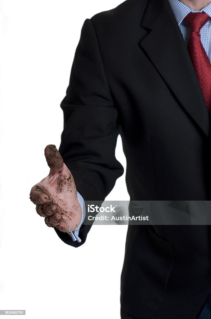 Dirty Handshake A well-dressed businessman offers a handshake with a soiled hand.  A metaphor for unscrupulous business dealings.  Shot in studio and converted from RAW file with 16 bit processing. Concepts Stock Photo