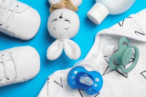 Flat lay composition with pacifiers and other baby stuff on light blue background
