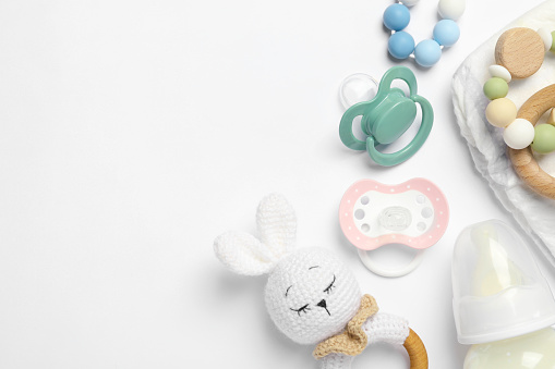 Flat lay composition with pacifiers and other baby stuff on white background. Space for text