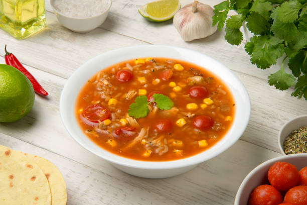 istock Easy Mexican chicken and rice soup in a white soup bowl on a rustic white table with ingredients. 1824819601