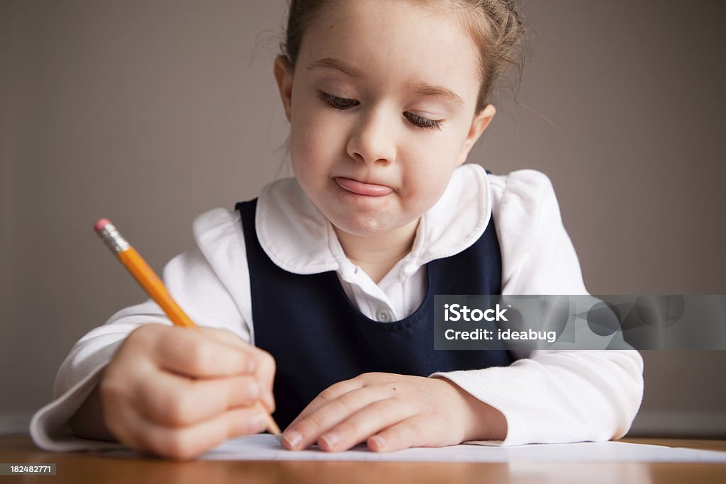 Garota jovem estudante escrever sentado em uma mesa de Escola - Foto de stock de 6-7 Anos royalty-free