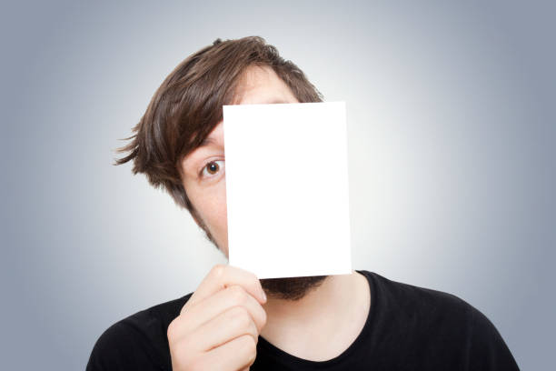 młody człowiek peeping od tyłu kartkę papieru - trzymanie za ręce zdjęcia i obrazy z banku zdjęć