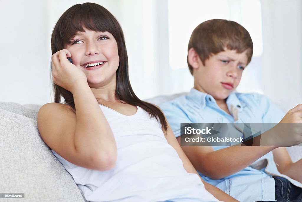Menina comunicação sobre cellphone com seu irmão na parte de trás - Royalty-free 10-11 Anos Foto de stock