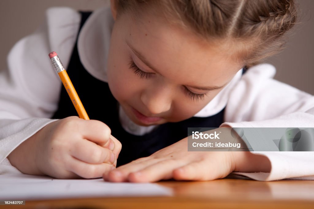 Giovane ragazza studenti scrivendo mentre seduto alla scrivania - Foto stock royalty-free di 6-7 anni