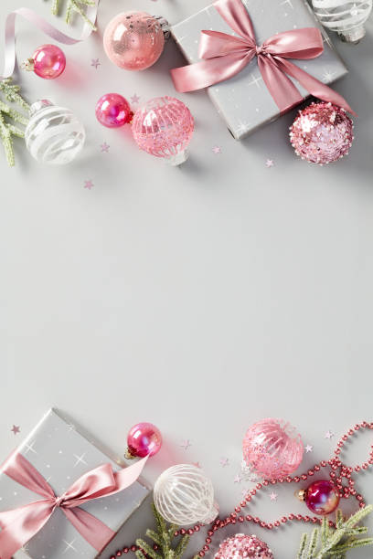 istock Elegant vertical Christmas background with chic gift boxes, pink baubles, decorations on grey table. 1824840836