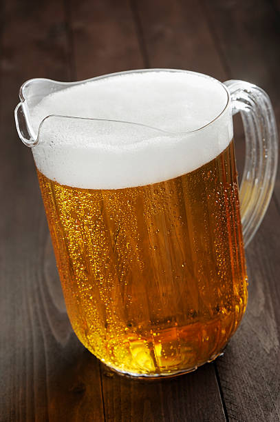 Pitcher of foamy beer on a wooden table stock photo