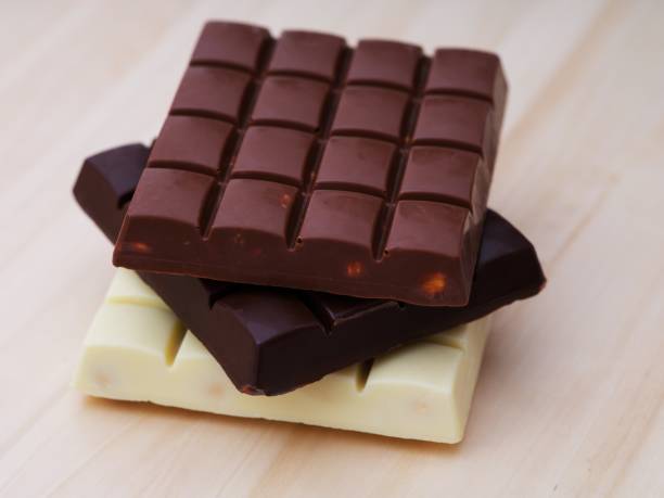 istock Milk, dark and white chocolate bars in stack on a wooden background. 1824841886