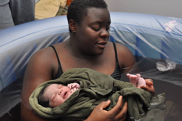 Baby Day~ Water Birth; checking toes mother in birthing tub examines newborn's feet water birth photos stock pictures, royalty-free photos & images
