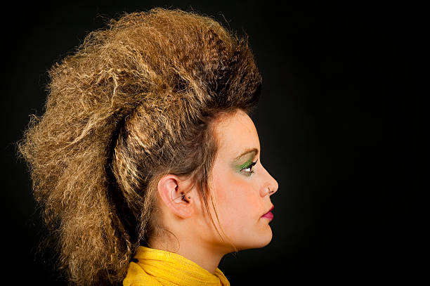 Portrait of a real female teenager with make-up and punk hairstyle.Female teenager with a nose piercing over a black background. Studio shot.