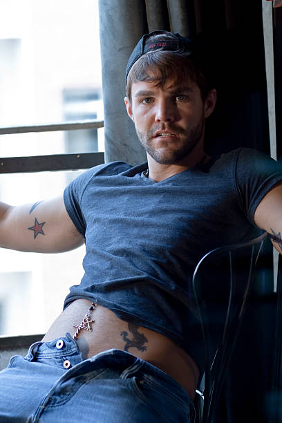 uomo rilassante su una sedia - stubble men tattoo sensuality foto e immagini stock