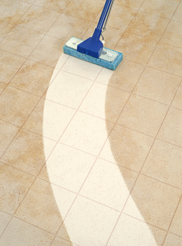 A sponge mop cleaning a path across a dirty tile floor.More cleaning paths: