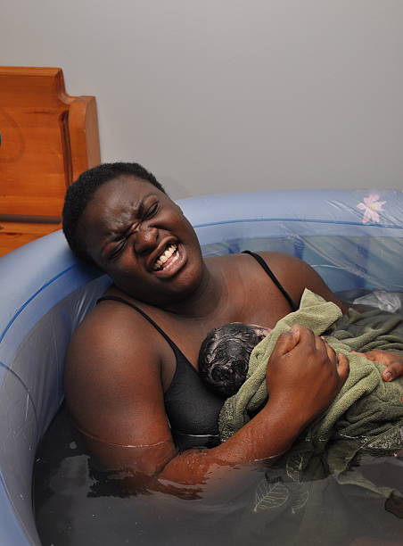 Baby Day~Water Birth; Mother and Newborn the face says it all as mother winces from after-pains  water birth stock pictures, royalty-free photos & images