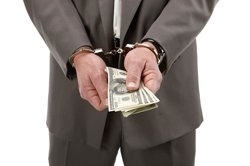 Business man in handcuffs giving money.