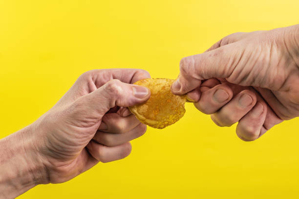 Potato chips in hand on yellow background stock photo