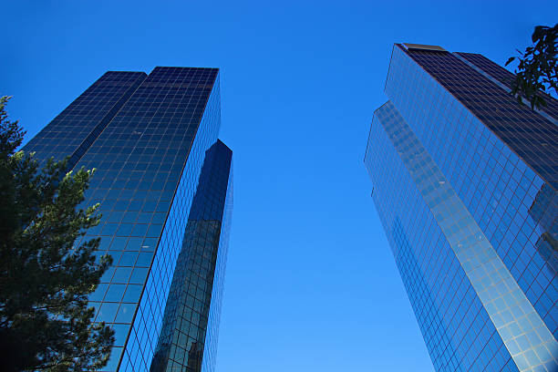 Recession Buildings Matching pair or blue glass buildings from low angle view with polarizing filter to pop those blues in the glass and sky to be a true 'business blue'; shot in Woodland Hills, CA and wide angle lens! Both buildings were a company that folded during recession with their insurance/financial services business woodland hills los angeles stock pictures, royalty-free photos & images