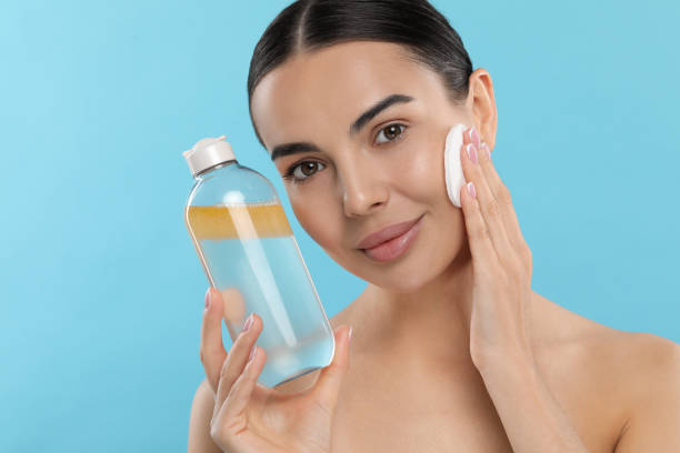istock Beautiful woman removing makeup with cotton pad on light blue background, space for text 1824860949