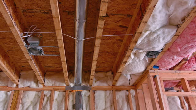 Worker installs hvac system, electrical wires, ceiling light, insulation before plasterboard
