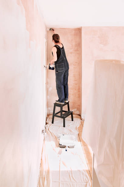 istock Woman painting newly plastered wall 1824873775