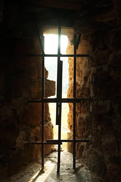 Prison Barred Window barred window of a prison with sunbeams dungeon medieval prison prison cell stock pictures, royalty-free photos & images