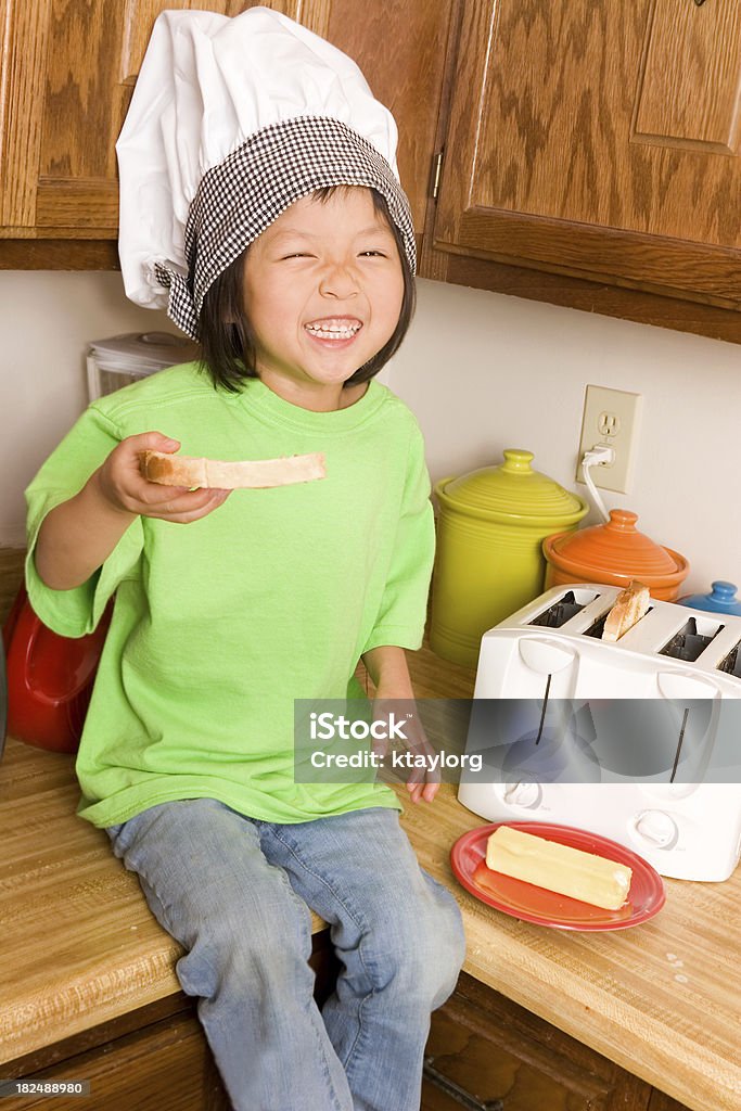 Cute preschooler ready to make toast Chinese little girl laughs as she attemps to make toast 2-3 Years Stock Photo