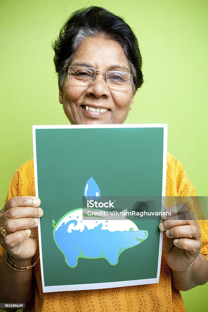 Senior Indian woman showing Save Water message sign poster leaflet Conceptual image showing the value of water and urging people to save it because it's more important than saving the money. 60-69 Years Stock Photo