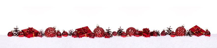 Red christmas balls with xmas gift boxes and pine cones in a row isolated on snow, christmas banner