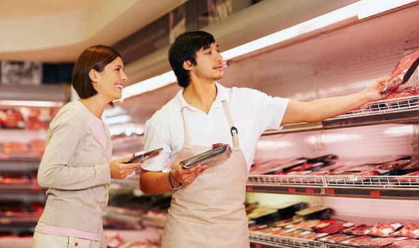 supermarkt mitarbeiter damit eine weibliche paket von fleisch sie - regalauffüller stock-fotos und bilder