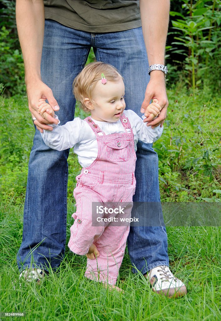 Adorabile bambina bambino imparare a piedi padre mano giardino - Foto stock royalty-free di 12-23 mesi