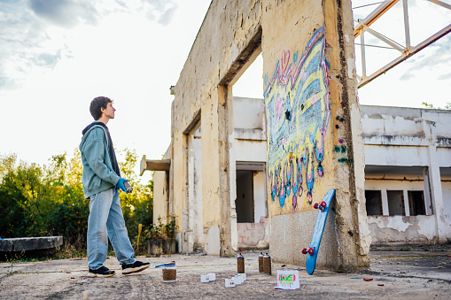 Young man creating graffiti on the wall of a abandoned building