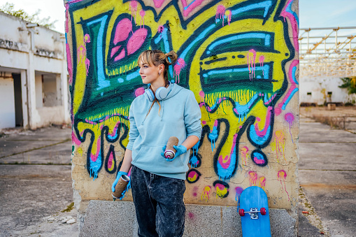 One male, male artist painting a graffiti on the wall on building top.