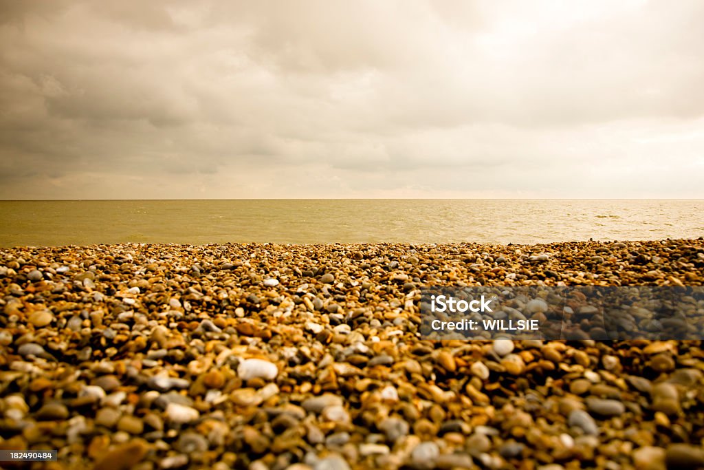 fine art style shingle beach with dramatic lit sky Simple shingle beach fine art style photograph with warm tones and a dramatically lit sky. Nobody. Focus on midground. Calm sea. Aldeburgh Stock Photo