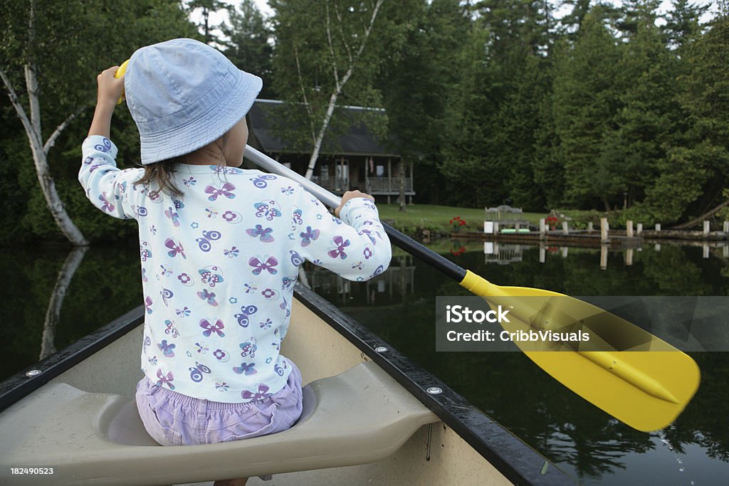 На улице молодая девушка Использовать вёсла каноэ на озере в направлении cabin - Стоковые фото Активный образ жизни роялти-фри