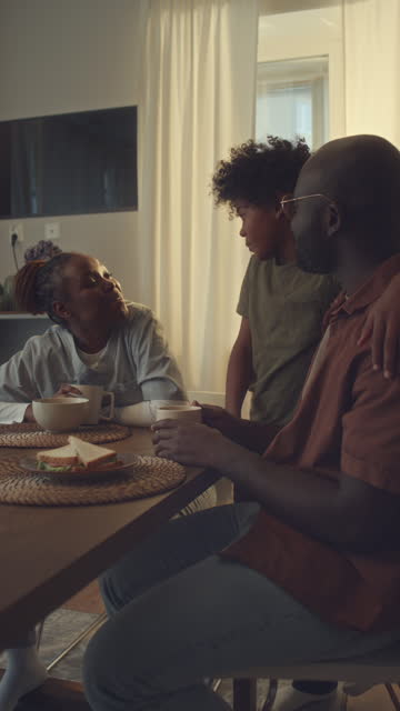 Black Woman in Nurse Uniform Chatting to Husband and Son over Breakfast