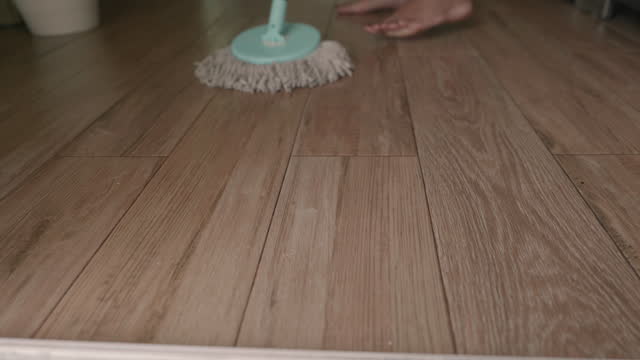 Asian woman mop the floor in the living room.