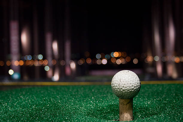 Tee Time at Night A golf Ball on tee at a driving range at night night golf stock pictures, royalty-free photos & images
