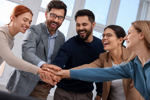 istock Team of employees joining hands in office 1824910583