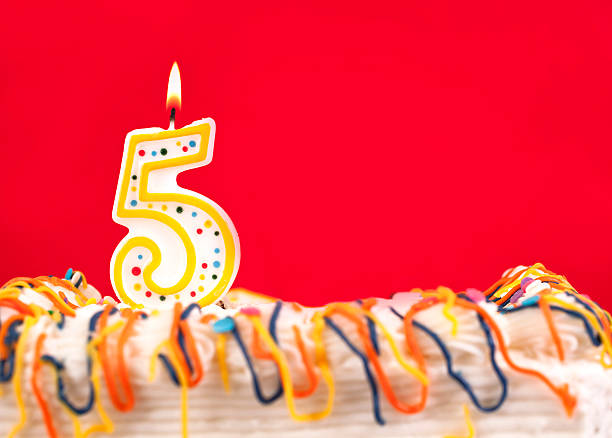 istock Decorated birthday cake with number 5 burning candle. Red background. 182491193