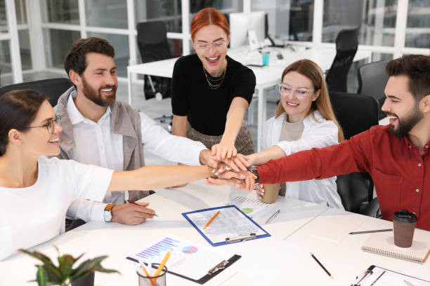 istock Team of employees joining hands in office 1824912218
