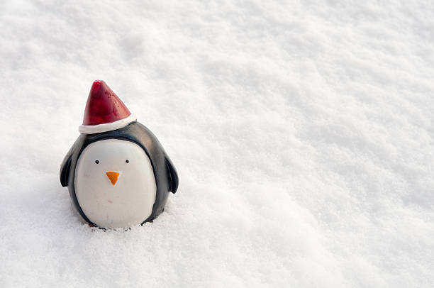 A nondescript Christmas decoration in the shape of a penguin stands all alone outside in the snow after escaping from a Christmas tree. Plenty of space for copy and text. ProPhoto RGB profile for maximum color fidelity and gamut.