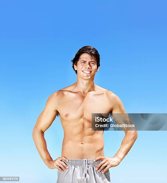 Sonriente Atractivo Muscular Guy De Pie Contra El Cielo Azul Foto de stock y más banco de imágenes de 20 a 29 años