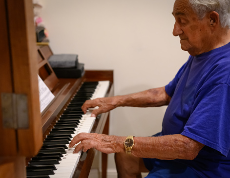 Senior adult man in his 90’s plays a piano, accomplished musician