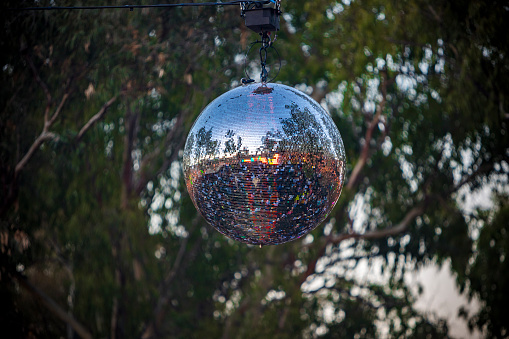 View of a disco ball hanging on a festival stage located in a forest. High quality photo