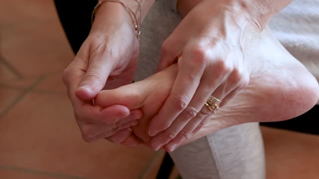 woman massaging her foot to relieve pain