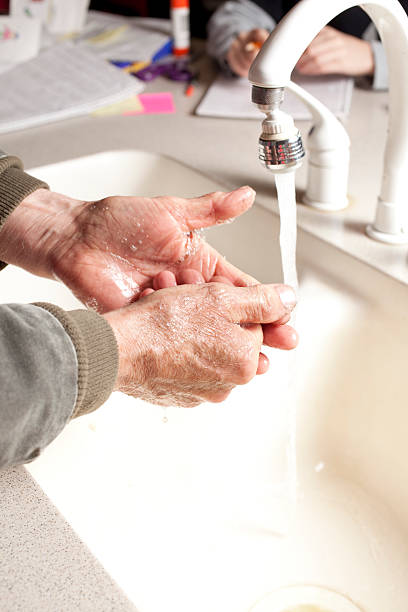istock Man at kitchen sink washing his hands. 182493429