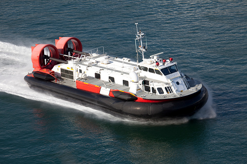 A coast guard hover craft travelling at a high rate of speed.