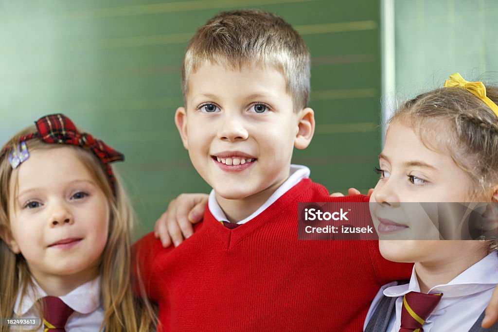 Happy School Kids Posing Together, Portrait "Portrait of a school boy and two girls embracing, smiling." 6-7 Years Stock Photo