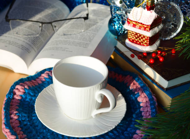 An empty cup for tea or coffee against a background of books and green Christmas tree branches. Decorations for the New Year and Christmas.
