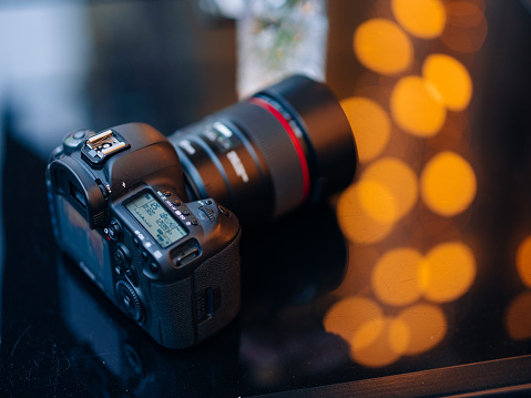 Close up view to professional digital camera with LCD screen on a blurred background with bokeh effect.